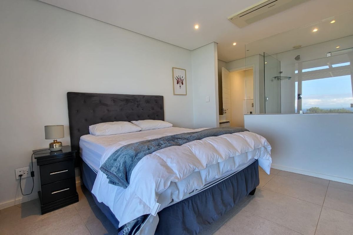 Modern bedroom featuring tiled flooring, recessed lighting, ducted air conditioning, and an integrated en-suite bathroom with a glass partition wall.