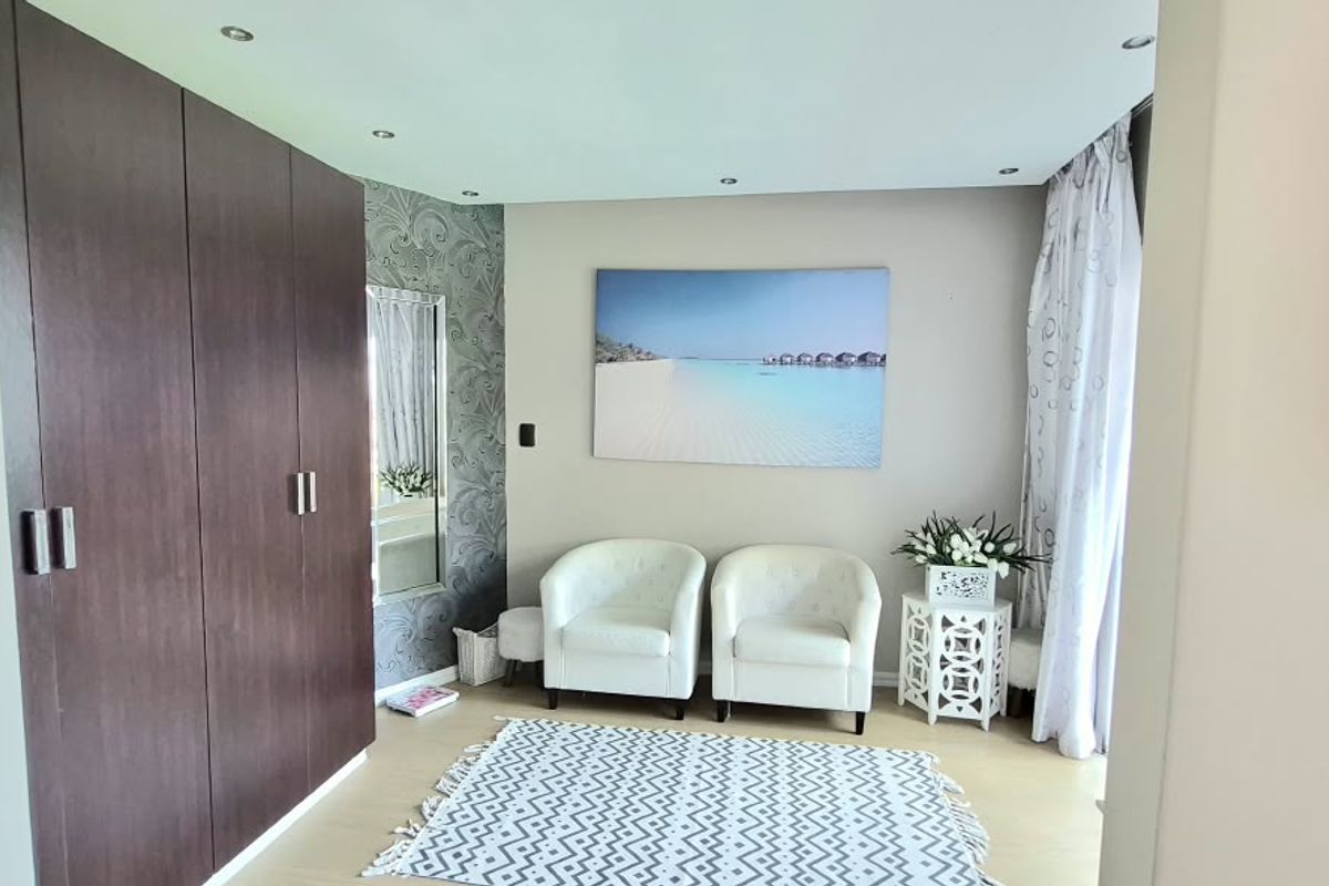 A well-maintained bedroom featuring dark wood built-in cupboards, recessed downlighting, and light-toned laminate flooring.