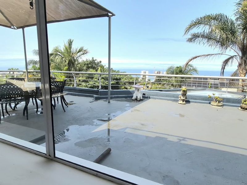 Spacious outdoor balcony featuring a metal railing and covered patio area with scenic coastal views.