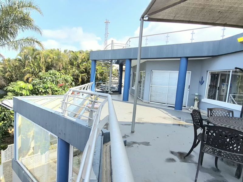 Spacious elevated balcony featuring a metal balustrade, shade sail, and direct access to the interior through sliding glass doors.