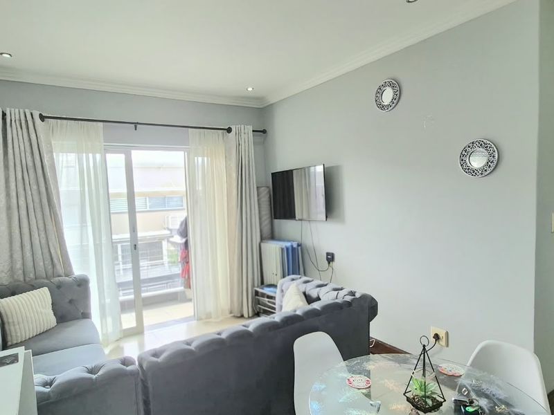 Open plan living area featuring tiled flooring, recessed downlights, and a sliding glass door leading to a balcony.