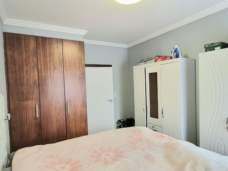 A bedroom featuring a built-in wooden wardrobe, crown molding, and neutral wall finishes.