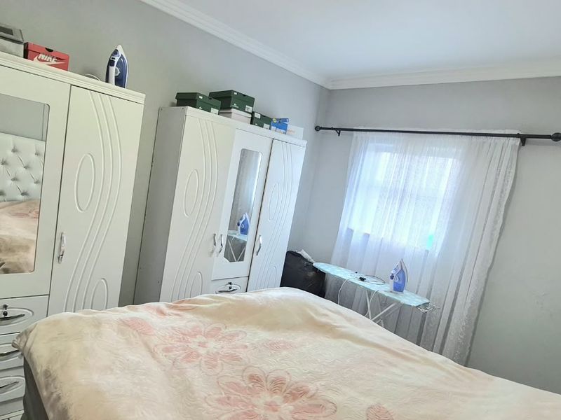 A bedroom featuring neutral wall tones, crown molding, and a window fitted with a curtain rod.
