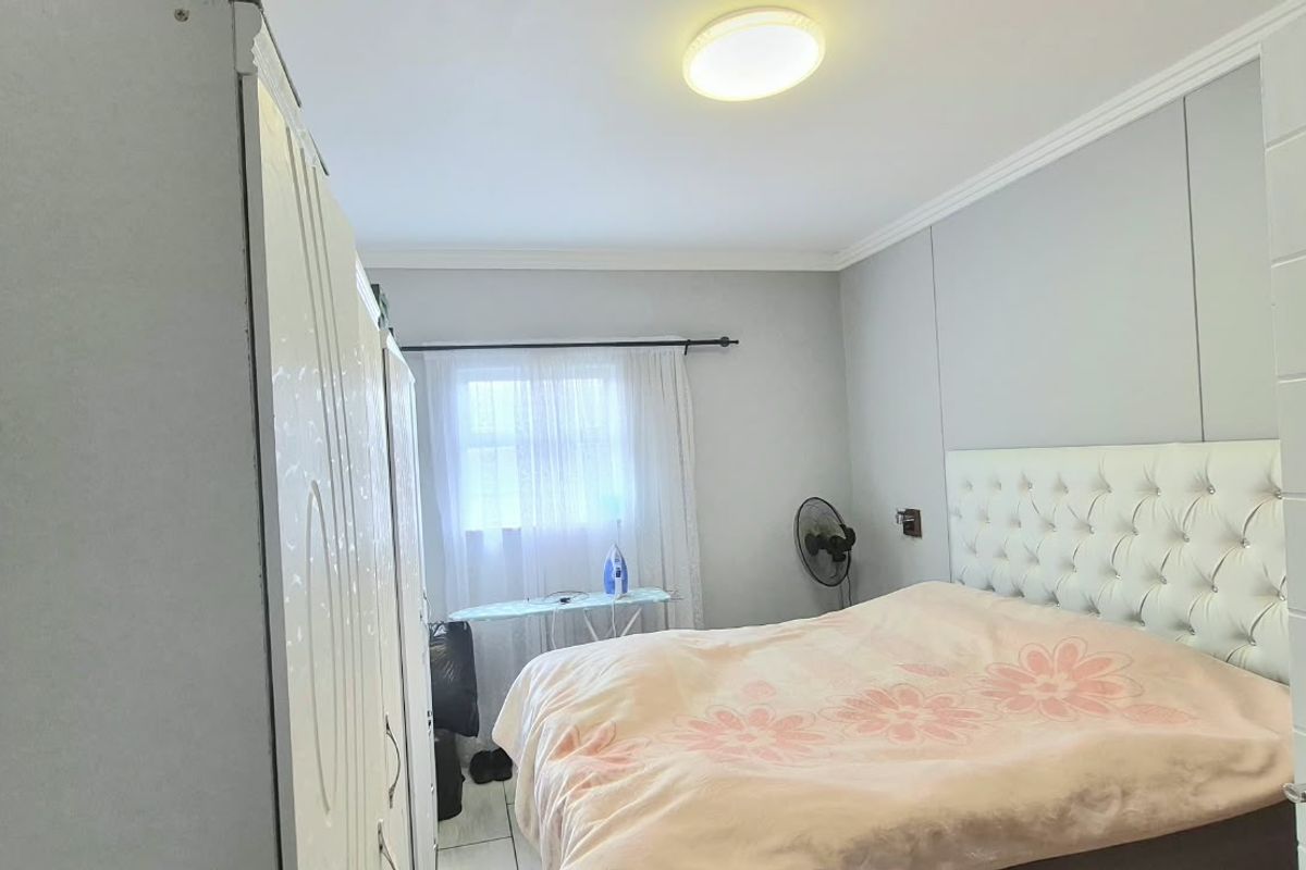 A functional bedroom featuring tiled flooring, coving, and a built-in wardrobe, providing a clean and neutral space for rest.