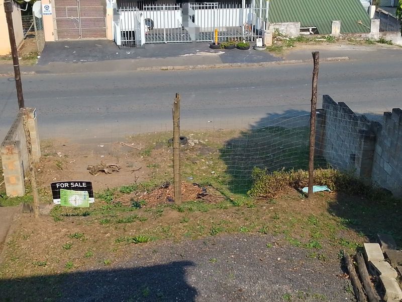 Front exterior view of the property featuring a gravel driveway, concrete block boundary walls, and wire mesh fencing facing the street.
