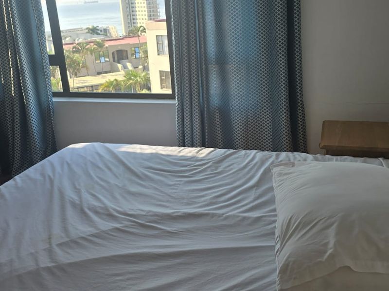A bedroom featuring a large window with natural light and views, providing a functional space for rest.