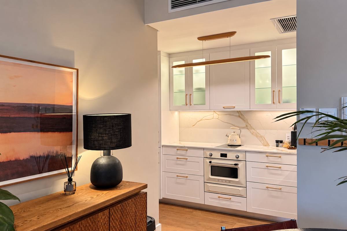 Modern kitchen featuring white cabinetry, integrated oven, cooktop, and elegant stone splashback with warm under-cabinet lighting.