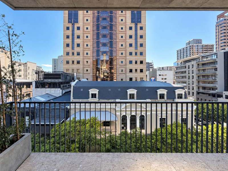 A modern balcony featuring stone tiling, a sleek metal balustrade, and a built-in planter box, offering an expansive urban city view.