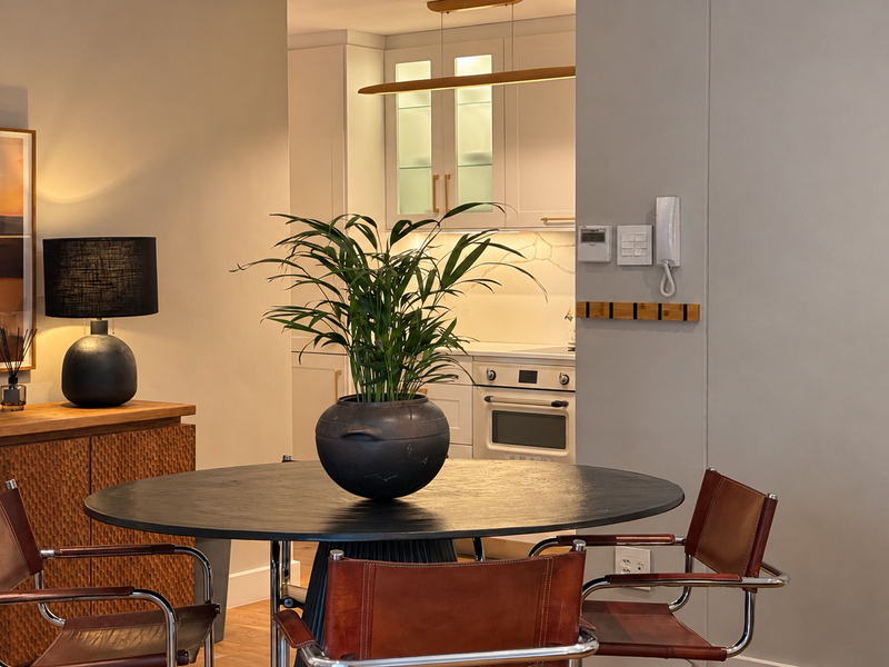 A well-appointed open-plan dining area featuring timber flooring, leading into a modern kitchen with built-in cabinetry and integrated oven.