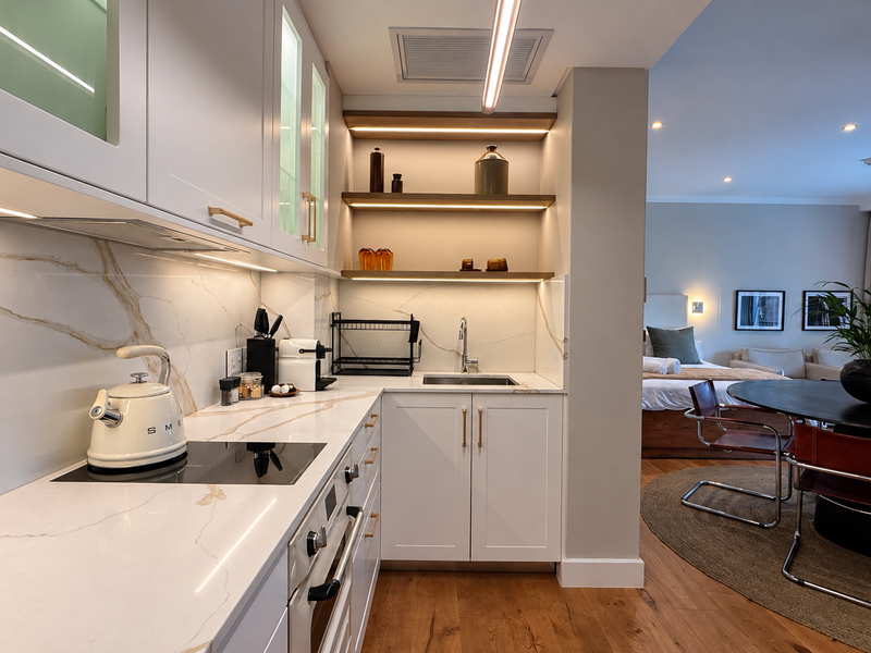 Modern open-plan kitchen featuring high-end marble-look stone countertops, integrated appliances, and sleek cabinetry, seamlessly flowing into the adjacent living and dining area.