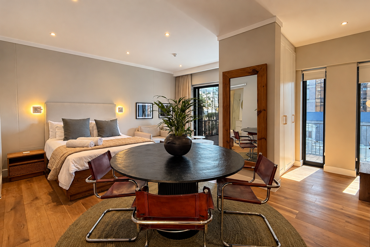 A well-appointed bedroom featuring hardwood flooring, recessed lighting, and a built-in wardrobe, with direct access to a private balcony.