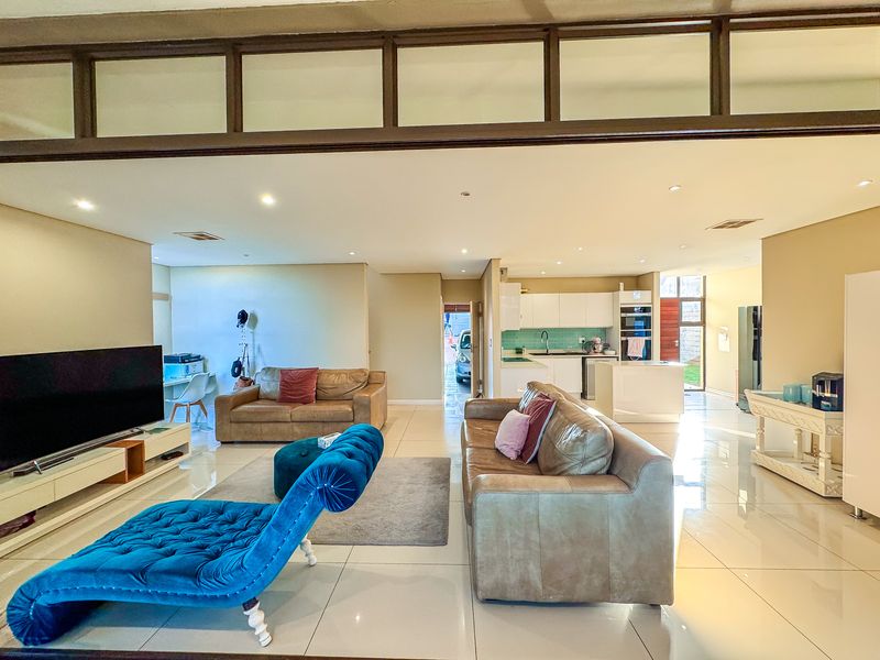 Spacious open-plan living area featuring polished tile flooring, recessed lighting, and a modern kitchen with built-in cabinetry and integrated appliances.