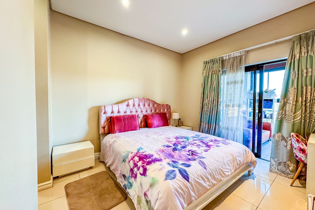 A well-maintained bedroom featuring tiled flooring, recessed downlighting, and a sliding glass door providing access to an outdoor area.