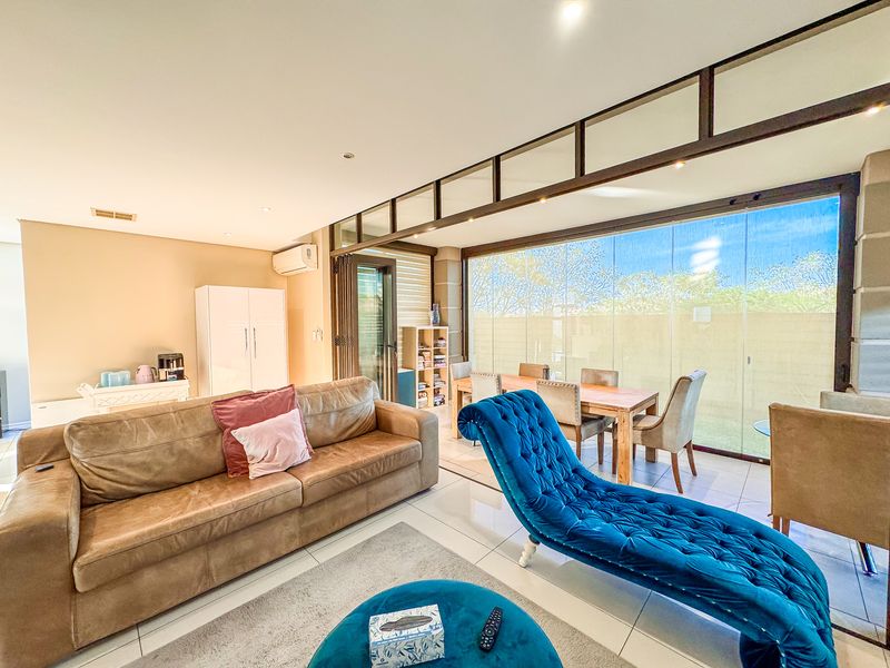 Spacious open-plan living and dining area featuring tiled floors, recessed lighting, and large stacking glass doors that provide seamless access to the outdoors.
