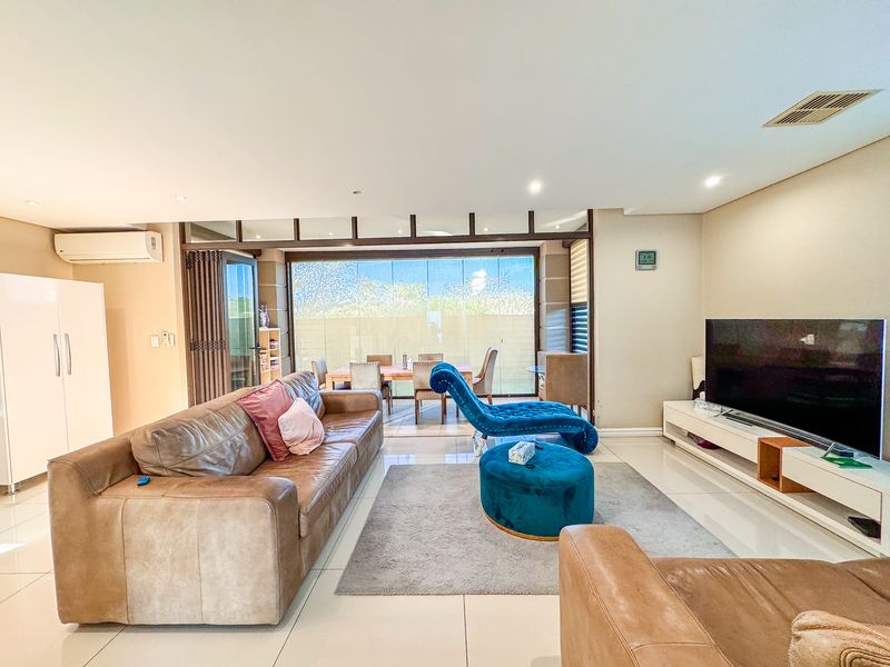 Spacious open-plan living area featuring tiled floors, recessed lighting, and large sliding glass doors providing seamless access to the outdoor patio area.
