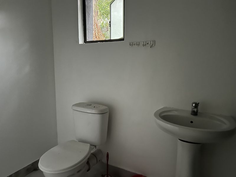 A basic bathroom featuring a pedestal basin and toilet, requiring cosmetic updates and cleaning to improve its overall condition.