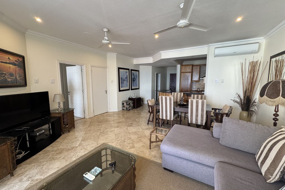 Spacious open-plan living and dining area featuring tiled floors, ceiling fans, and a split-system air conditioner, seamlessly connected to the kitchen.