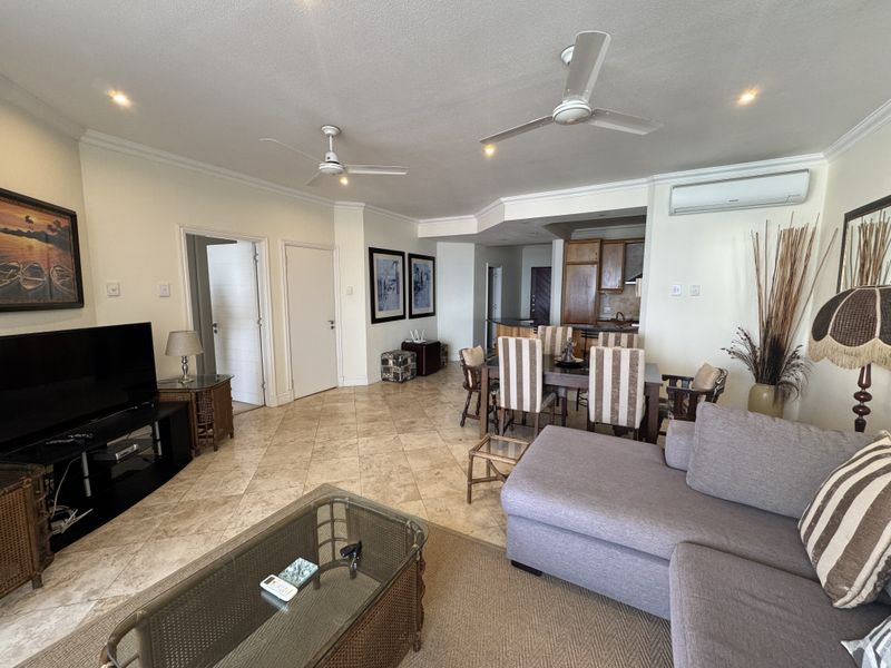 Spacious open-plan living and dining area featuring tiled floors, ceiling fans, and a split-system air conditioner, seamlessly connected to the kitchen.