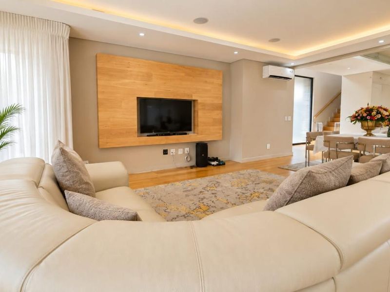 Spacious open-plan living area featuring hardwood flooring, recessed cove lighting, a timber feature wall, and integrated air conditioning.