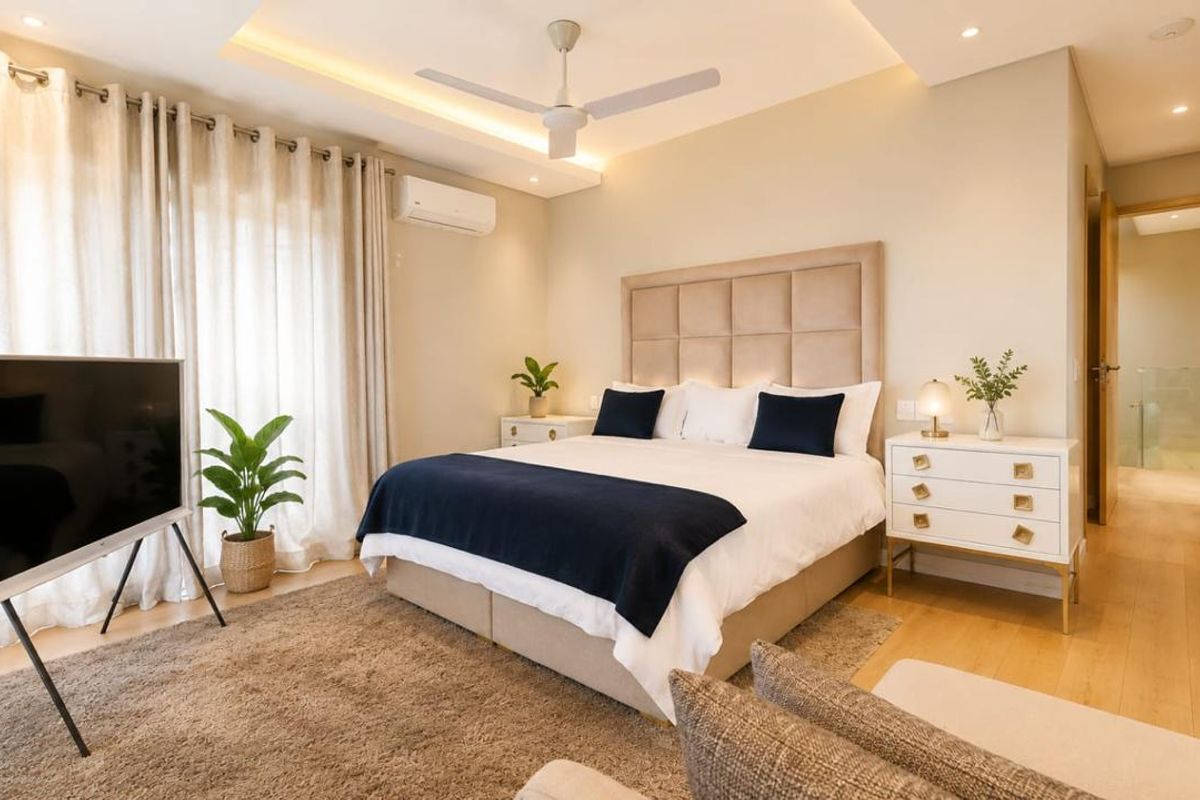 A well-appointed bedroom featuring recessed ceiling lighting, a ceiling fan, split-system air conditioning, and light hardwood flooring.