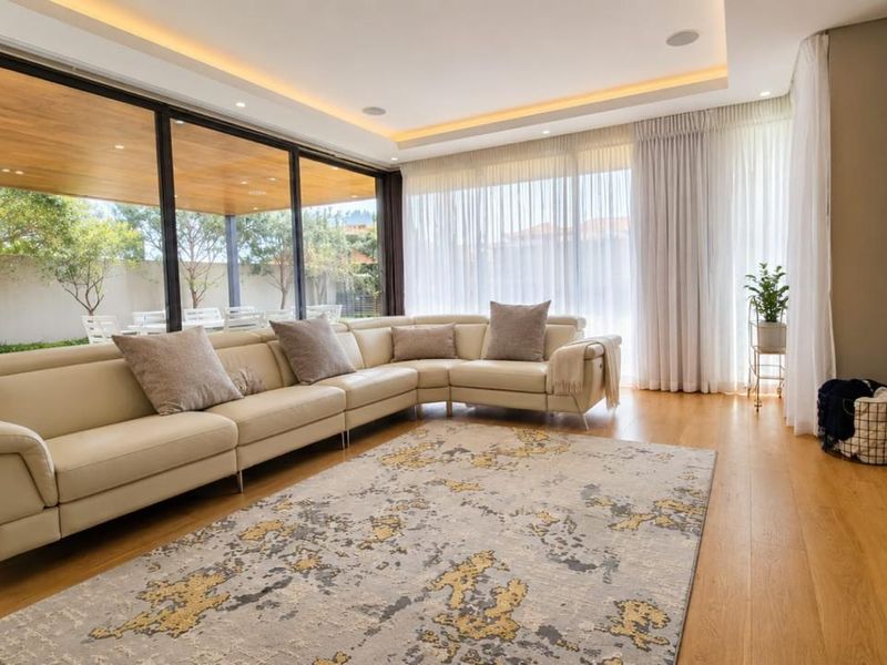 Modern living room featuring hardwood floors, recessed ceiling lighting, integrated speakers, and large sliding glass doors opening to an outdoor patio area.