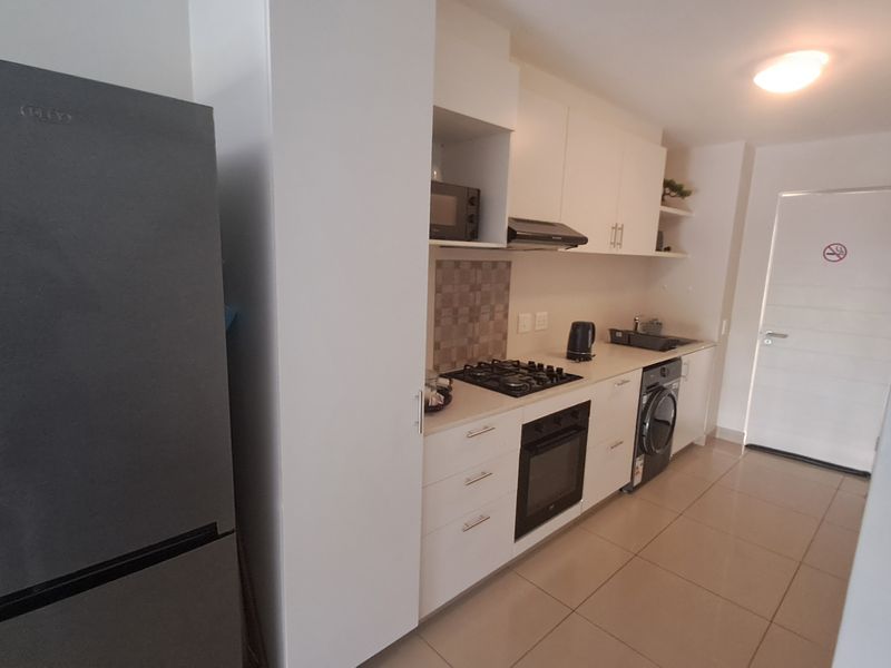 Modern kitchen featuring white cabinetry, gas hob, built-in oven, extractor fan, and tiled flooring, offering a clean and functional workspace.