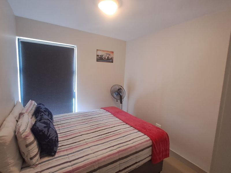 A compact bedroom featuring neutral wall finishes, a roller blind, and a central ceiling light fixture.