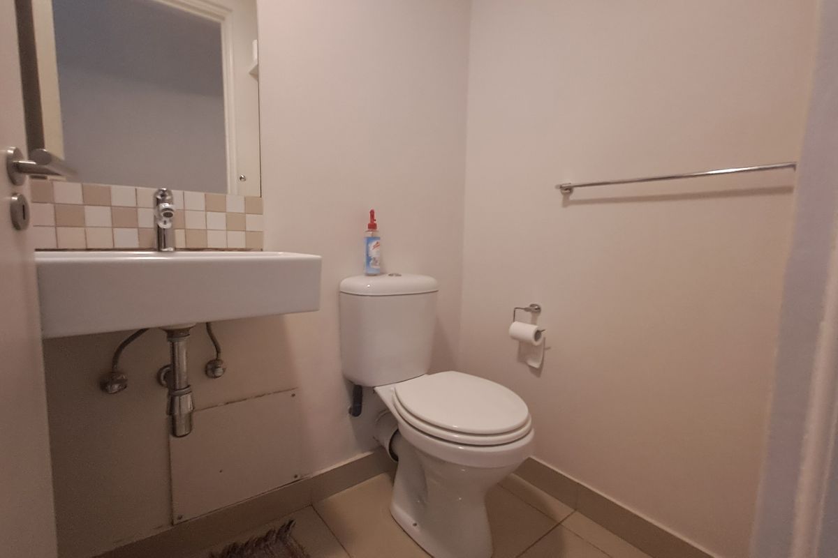 A compact guest bathroom featuring a wall-mounted basin, toilet, and tiled splashback, providing a functional and clean space.