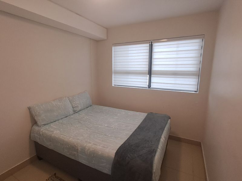 A simple bedroom featuring tiled flooring and modern roller blinds, providing a clean and functional space.