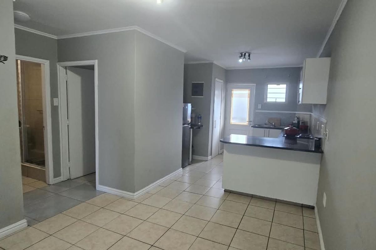 Open-plan living area featuring tiled flooring, a functional kitchen with breakfast nook, and neutral wall finishes.