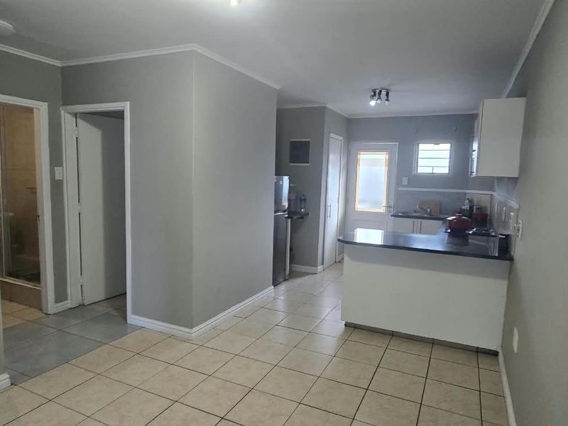 Open-plan living area featuring tiled flooring, a functional kitchen with breakfast nook, and neutral wall finishes.