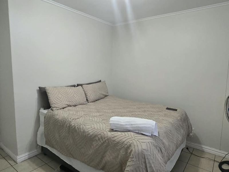 A simple bedroom featuring tiled flooring and neutral wall finishes, providing a functional and clean sleeping space.