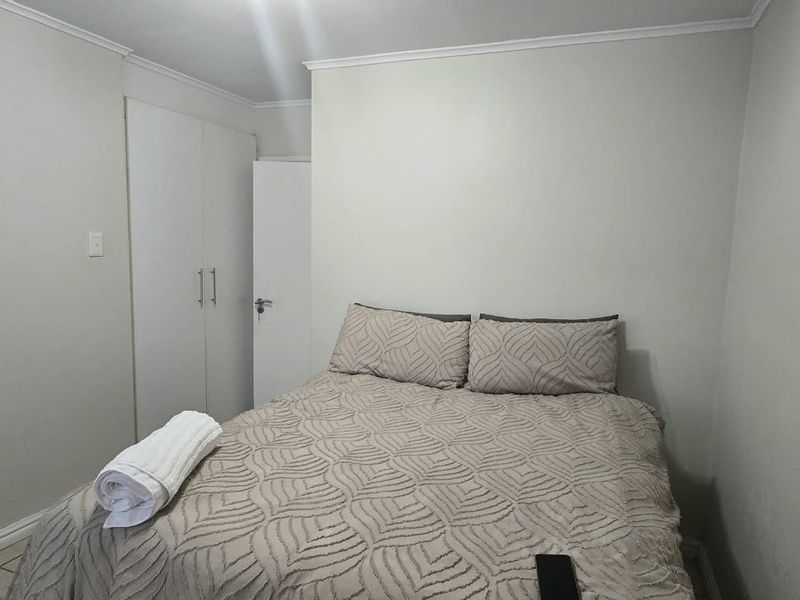 A functional bedroom featuring neutral walls, tiled flooring, and built-in cupboards for storage.