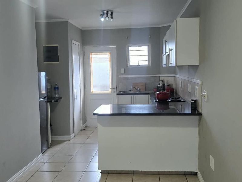 Functional kitchen featuring granite countertops, built-in cabinetry, and tiled flooring with direct access to an exterior door.