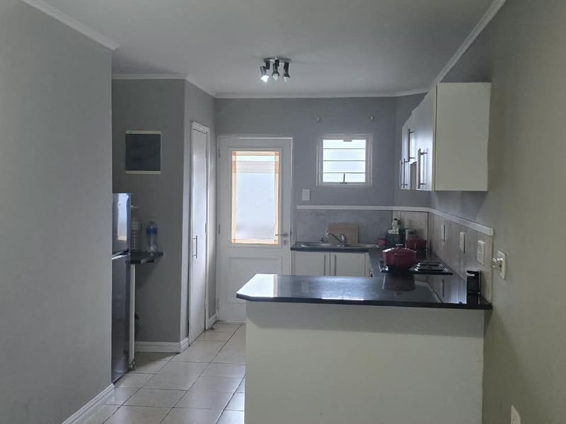 A functional kitchen featuring granite countertops, built-in cabinetry, and tiled flooring, with direct access to an exterior door.