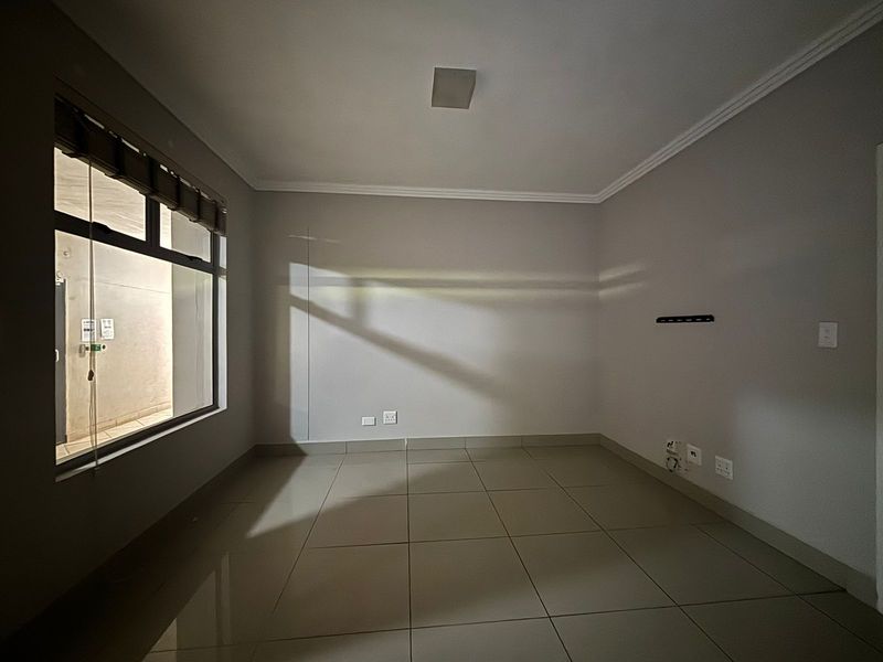 A clean, empty bedroom featuring neutral tiled flooring, modern skirting, and cove cornicing, providing a versatile space ready for personalization.