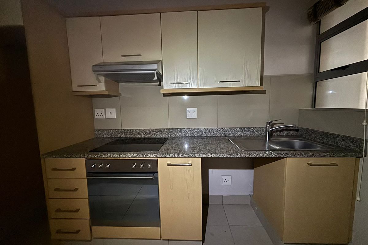 A functional kitchen featuring built-in cabinetry, granite countertops, an electric hob, oven, extractor fan, and a stainless steel sink.