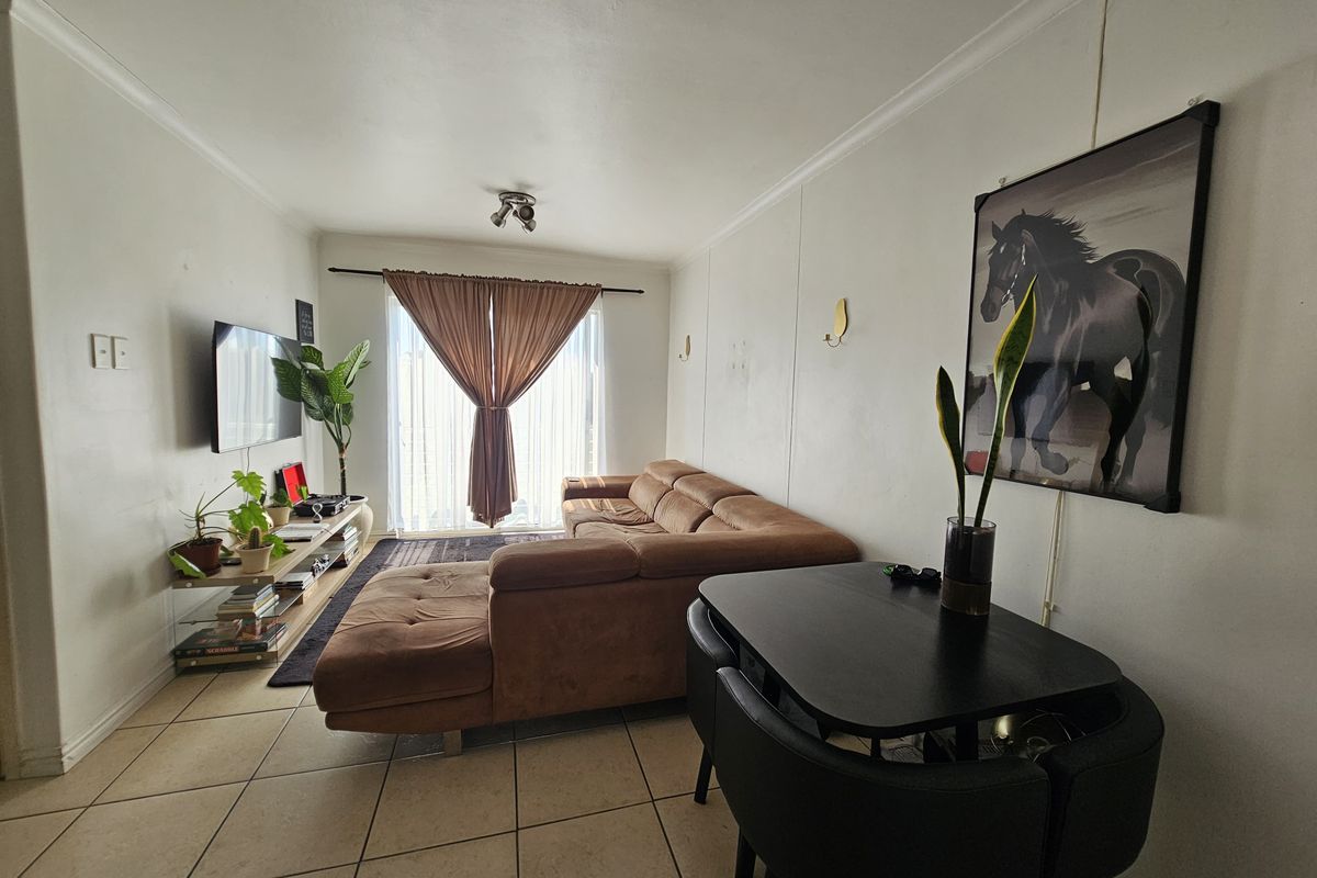 A functional living room featuring tiled flooring and a sliding glass door that provides natural light and access to the exterior.