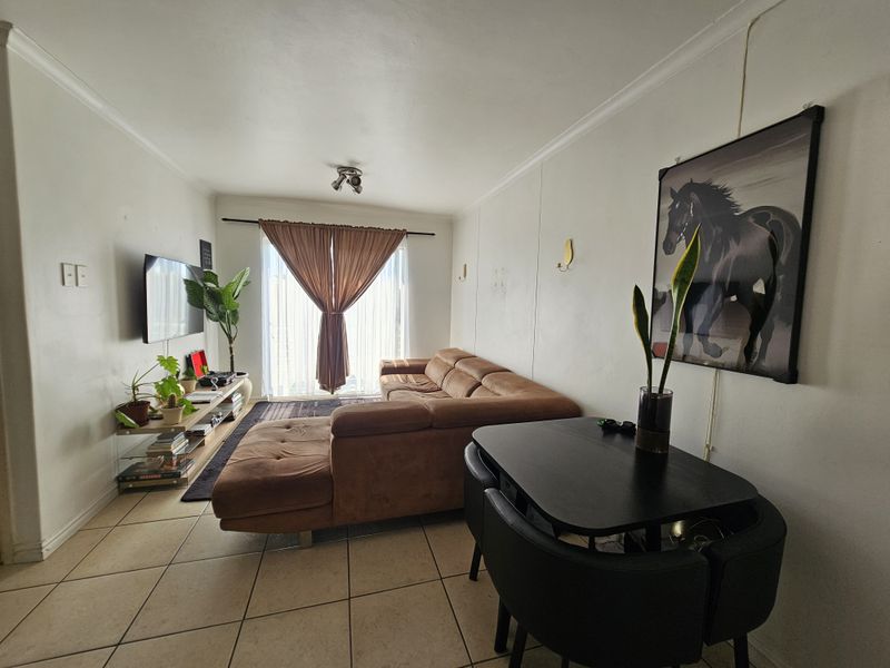 A functional living room featuring tiled flooring and a sliding glass door that provides natural light and access to the exterior.