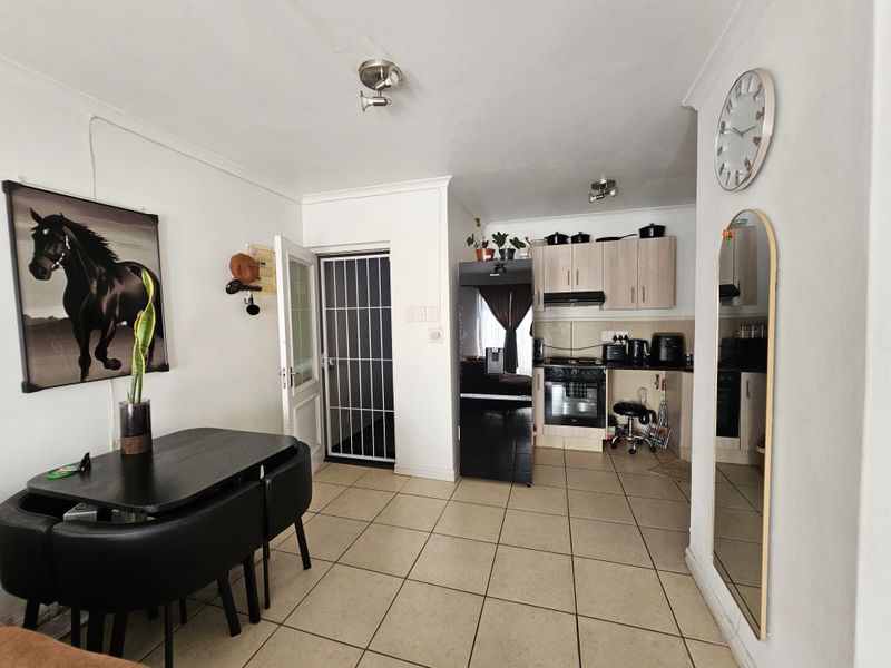 Open-plan living and kitchen area featuring tiled flooring, built-in cabinetry, and a secure entrance door.