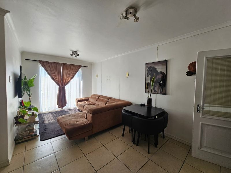 A living room featuring tiled flooring, coved ceilings, and a sliding glass door providing natural light.