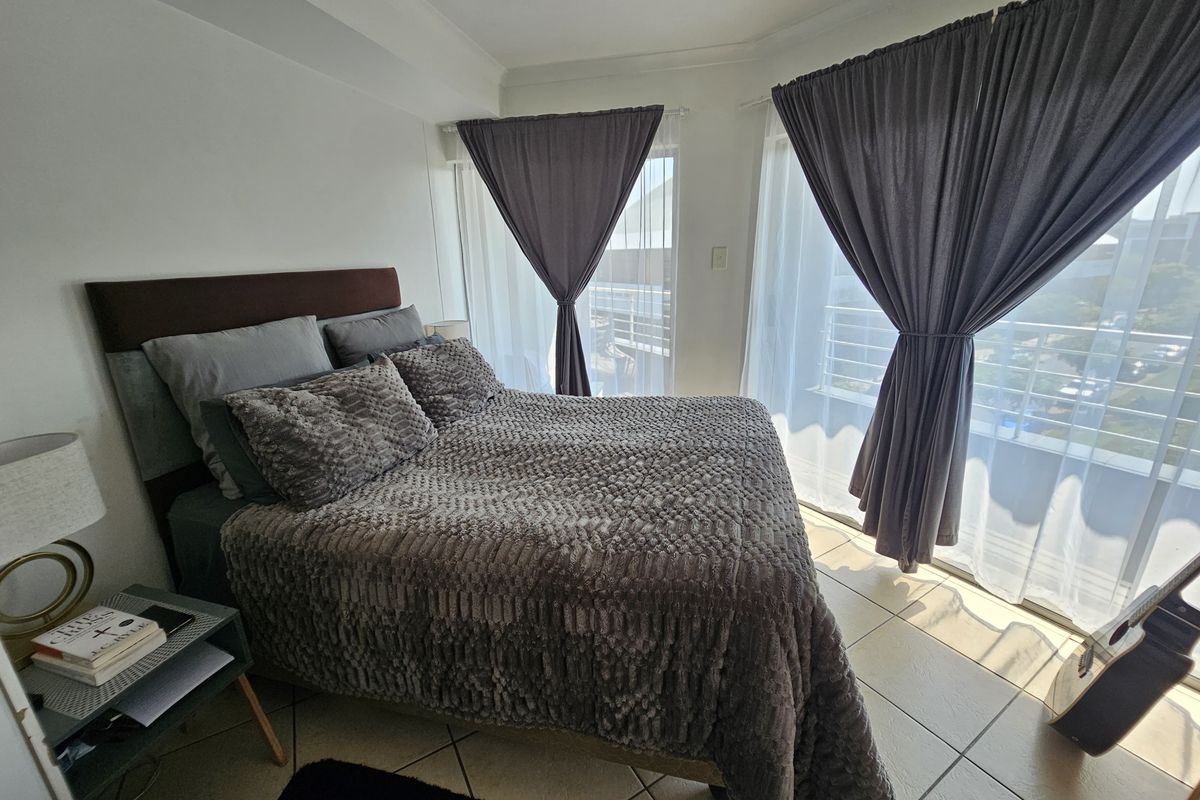 A bright bedroom featuring tiled flooring and large sliding glass doors that provide access to an outdoor balcony area.