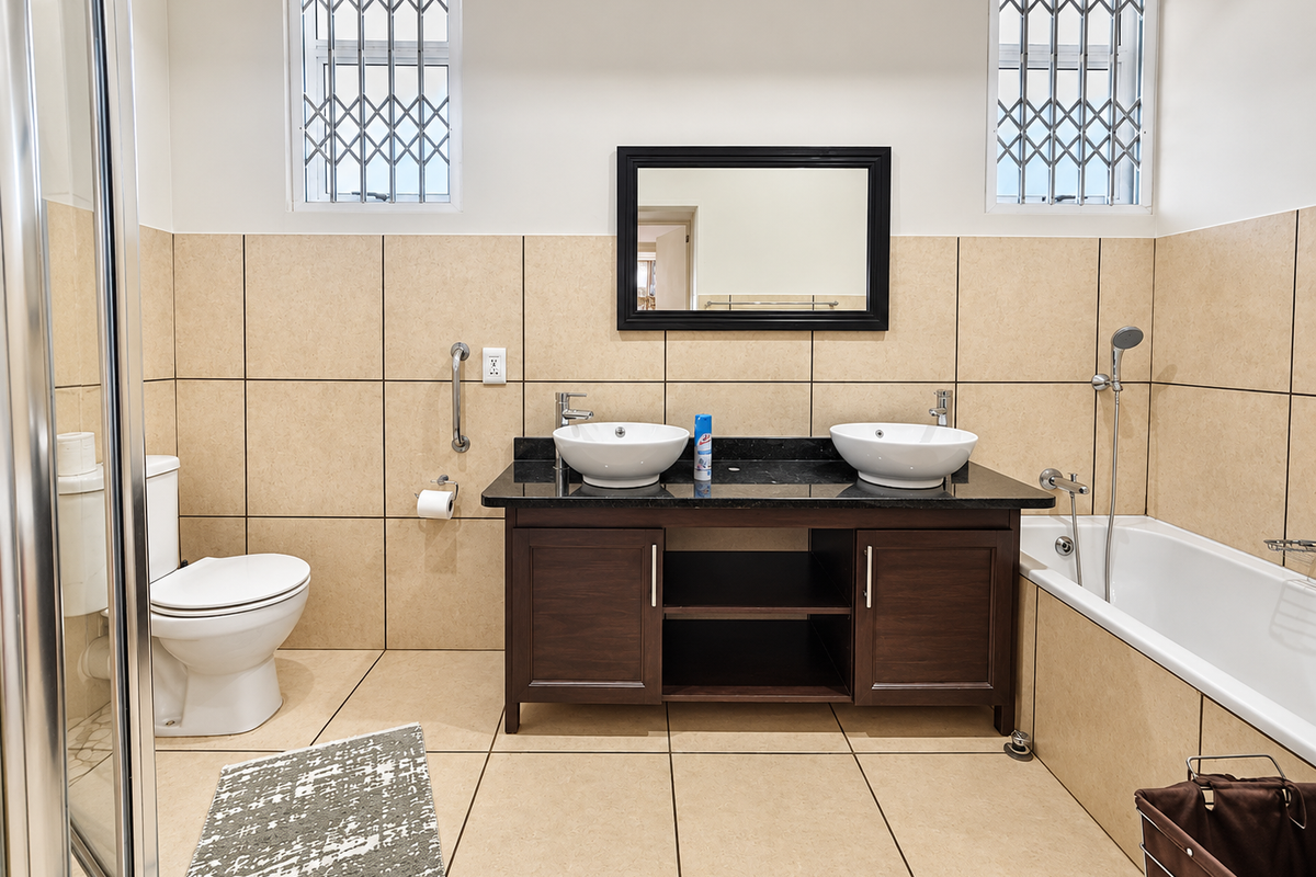A well-maintained bathroom featuring a double vanity with vessel sinks, granite countertop, bathtub, separate shower enclosure, and security-fitted windows.