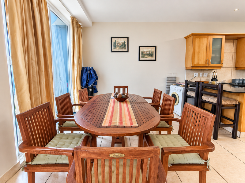 Open-plan living and dining area featuring tiled floors, wooden cabinetry, and large sliding glass doors leading to an outdoor space.