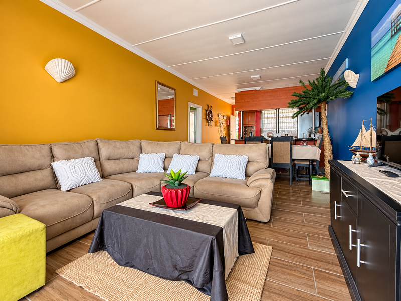 Open-plan living and dining area featuring tiled flooring, vibrant accent walls, and integrated air conditioning, providing a functional and connected living space.