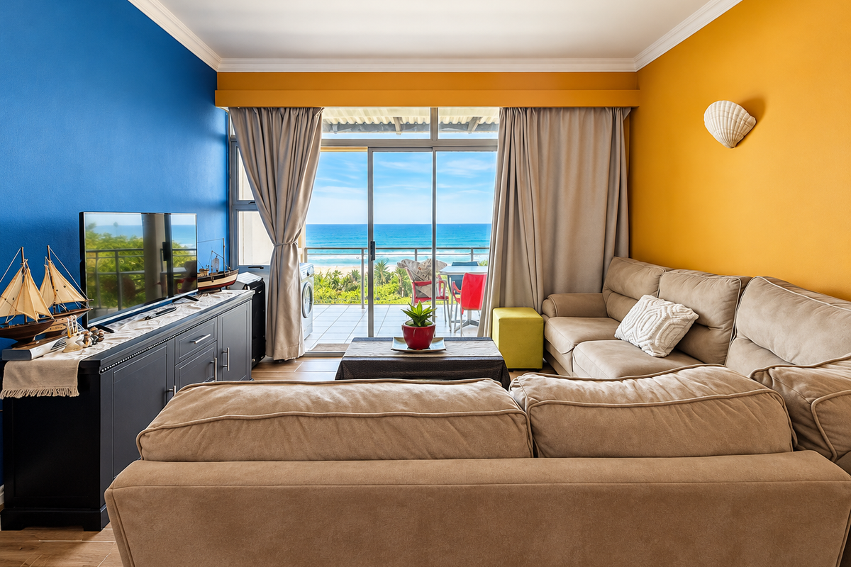 A bright living room featuring vibrant accent walls, tiled flooring, and large sliding glass doors that open to a balcony with ocean views.