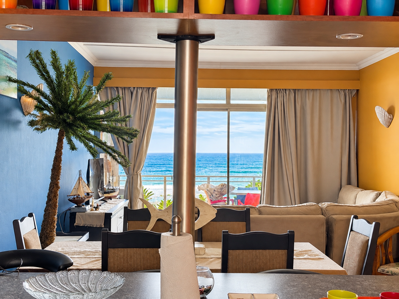 Open plan living and dining area featuring a central support column, recessed lighting, and large sliding glass doors opening to a scenic ocean view.