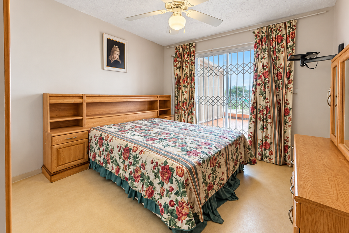 A bedroom featuring a ceiling fan, vinyl flooring, and a sliding glass door with a security gate leading to an outdoor area.