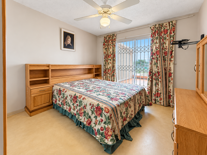 A bedroom featuring a ceiling fan, vinyl flooring, and a sliding glass door with a security gate leading to an outdoor area.