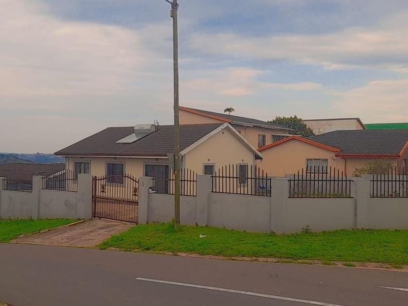 Front view of a single-story residential house featuring a perimeter wall, metal gate, and a solar water heating system on the tiled roof.
